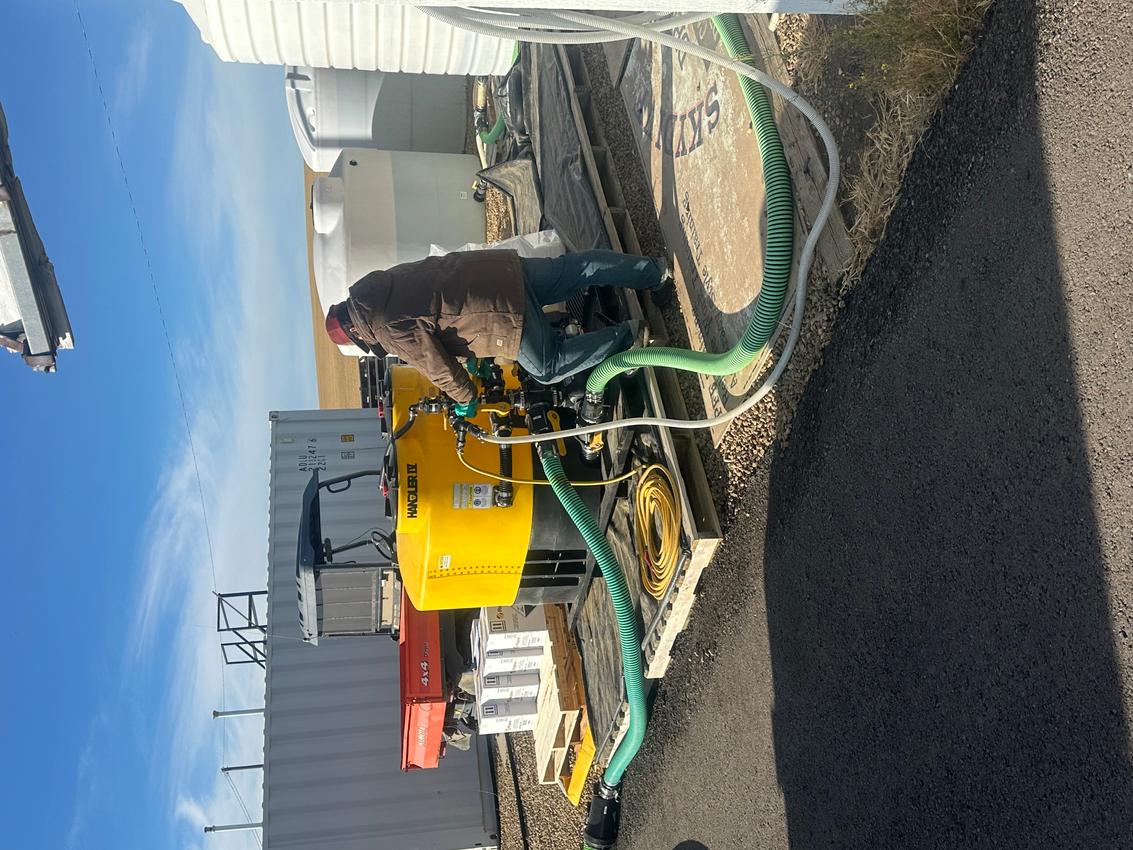 A image of a person operating a machine with an attached hose